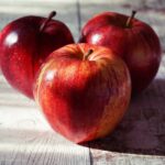 three red apples on wooden surface